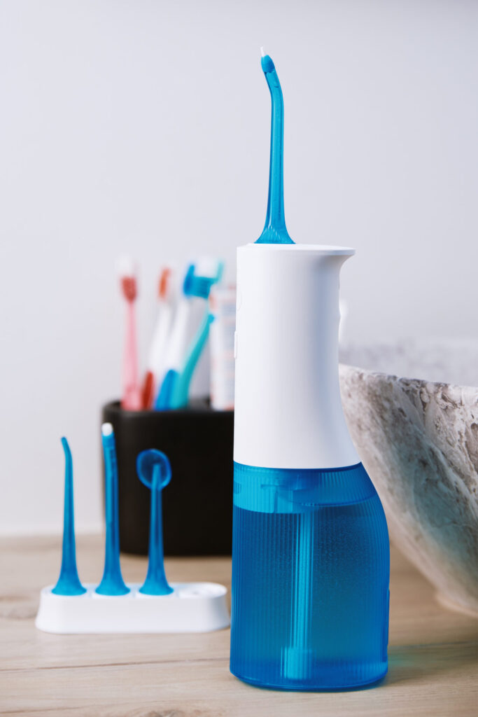 Blue home oral irrigator kit in bathroom, Waterpik for teeth cleaning, portable water flosser for dental care